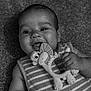 baby, black_and_white, chewing, child, closeup, cute, dinosaur_toy, face, hand, happy, infant, lying_down, monochrome, playful, portrait, sleeveless, smiling, striped_clothing, teething_toy, texture