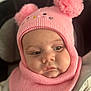 baby, child, face, headwear, hat, knit, pom_poms, pink, warm_clothing, cute, infant, portrait, closeup, soft_texture, cozy, expression, person, young_child, indoors, seated