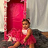 baby, child, toddler, portrait, sitting, smiling, pink_dress, party, birthday, celebration, confetti, photo_booth, decorations, stars, teddy_bear, indoors, blanket, baby_hair, bare_feet, happy