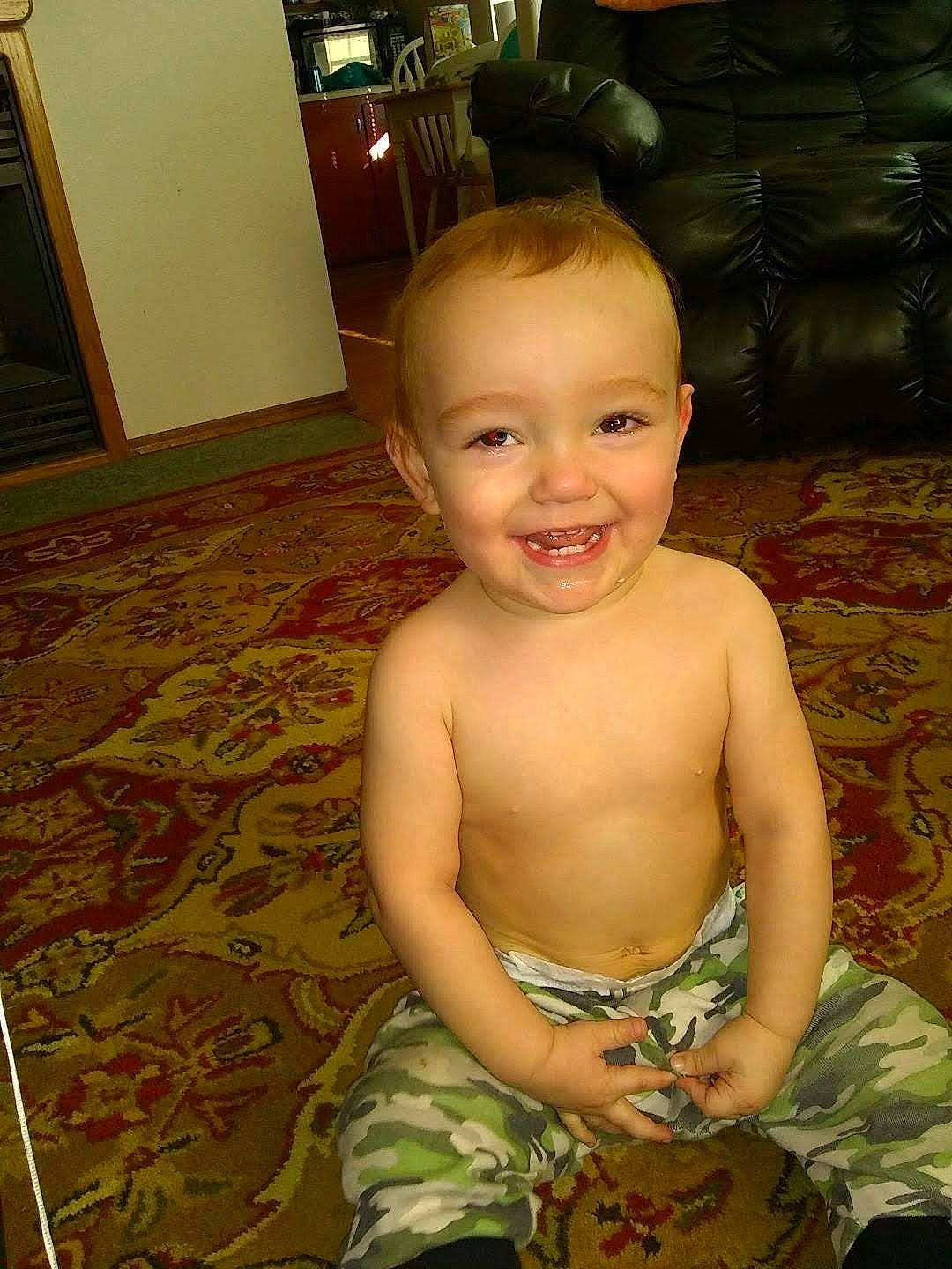 Luis is registered to the contest to win money with this photo: baby, cheek, chest, chin, eye, facial_expression, floor, flooring, fun, green, hair, hardwood, head, human_body, iris, joy, person, skin, smile, toddler