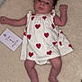 baby, infant, dress, hearts, blanket, crib, milestone_card, lying_down, wide_eyes, alert, cute, person, child, one_month, red_hearts, white_dress, skin, legs, arms, indoors