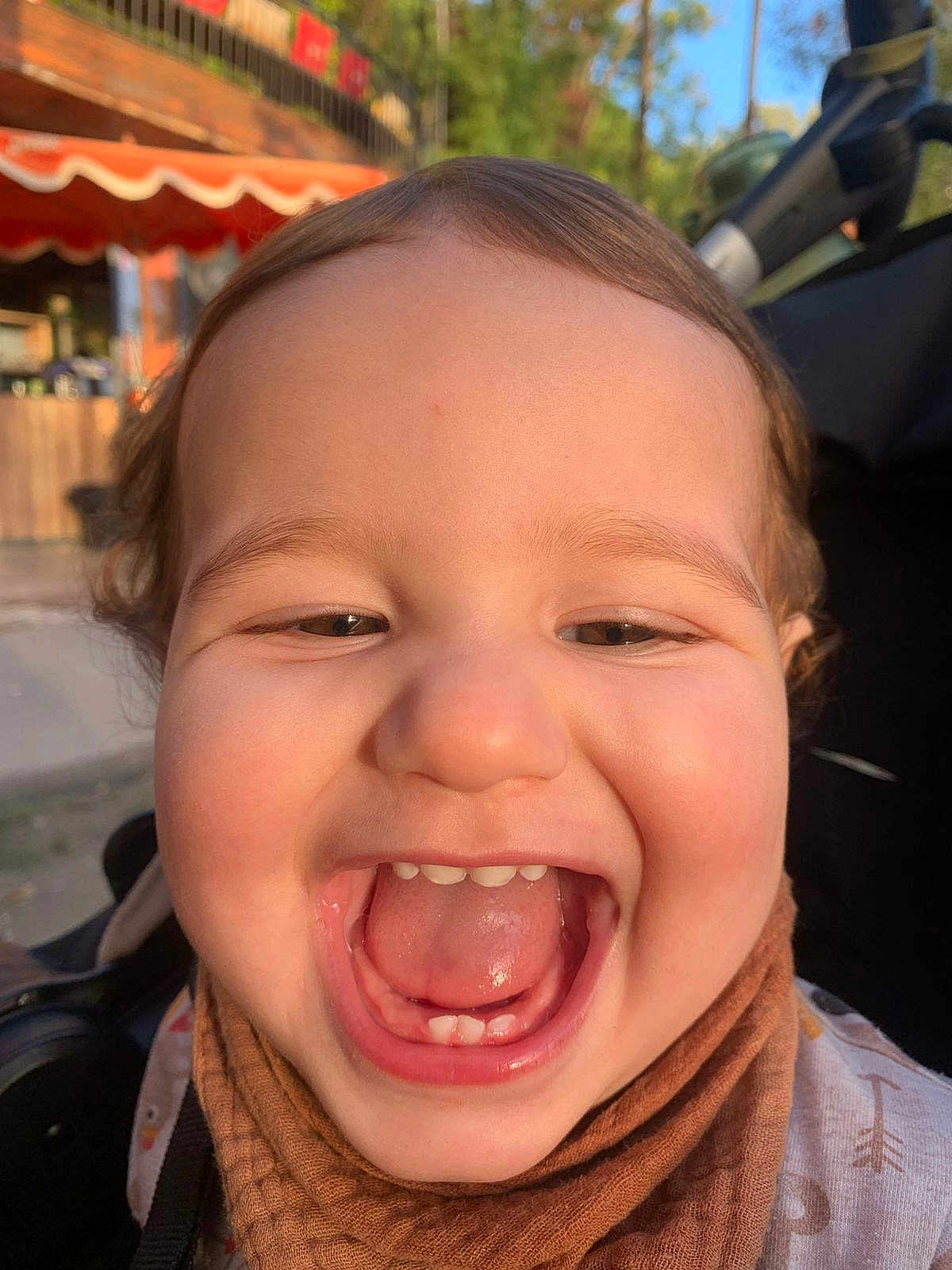 Lïon participe au concours pour gagner de l'argent avec cette photo : toddler, child, smile, happy, face, teeth, tongue, scarf, brown, outdoor, daylight, closeup, cute, person, baby, head, skin, expression, joy, warm