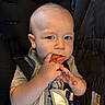 apparel, baby, bib, car_seat, casual, child, clothing, curious, expression, face, food, hand, indoor, nugget, person, seatbelt, sitting, snack, toddler, young_child