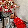 dog, sweater, red, christmas_tree, ornaments, wooden_tree, holiday, decorations, furry_bed, indoor, pet, cozy, festive, small_dog, side_view, looking_away, living_room, gray_bed, holiday_decor, cute