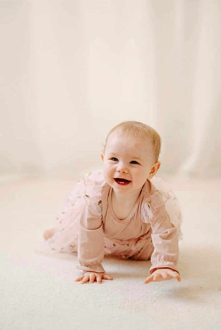 Freya is registered to the contest to win money with this photo: baby, child, crawling, smiling, pink_dress, long_sleeves, floor, carpet, indoor, portrait, cute, happy, young_child, infant, person, toddler, light_skin, blonde_hair, soft_lighting, neutral_background