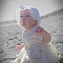 baby, child, infant, beach, sand, dress, hat, sun_hat, outdoor, portrait, cute, sitting, white_clothing, young_child, soft_light, curious, nature, daytime, small_hand, face