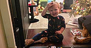 Zander is registered to the contest to win money with this photo: toddler, child, smiling, indoor, pajamas, toys, toy_cars, wooden_floor, christmas_tree, holiday_decor, cat, orange_cat, holiday_lights, happy, playtime, floor, animal, home, cute, festive