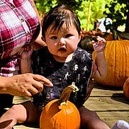 Ezra joined the competition — help win amazing prizes! baby, child, pumpkin, autumn, halloween, outdoor, porch, wooden_deck, garden, foliage, plaid_shirt, skeleton_pattern, infant, sitting, waving, smiling, portrait, family, daylight, seasonal