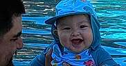 Ezra joined the competition — help win amazing prizes! baby, child, infant, adult, parent, smiling, happy, blue_clothing, cap, pool, water, swimming, outdoor, portrait, close_up, holding, family, face, ripples, summer