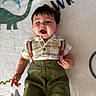 Ezra joined the competition — help win amazing prizes! baby, child, infant, portrait, lying_down, smiling, surprised, open_mouth, dinosaur, blanket, indoor, clothing, suspenders, shorts, green, face, dark_hair, eyes, playful, photography
