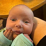 Oliver is registered to the contest to win money with this photo: arm, baby, can, chubby_cheeks, closeup, clothing, curious, cute, expression, eyes, face, hand, holding, indoor, infant, mouth, person, resting, skin, table