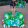 animal, canine, daylight, dog, ears_up, frog_sculpture, fun, german_shepherd, green, nature, outdoor, park, pet, play, playground, sculpture, slide, tongue_out, trees, wood_chips