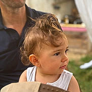 Esteban a rejoint le concours — aidez-le/la à gagner de superbes lots ! toddler, child, curly_hair, face, person, adult, hand, outdoor, grass, white_shirt, portrait, baby, skin, head, holding, background_blur, casual_clothing, nature, daylight, curious