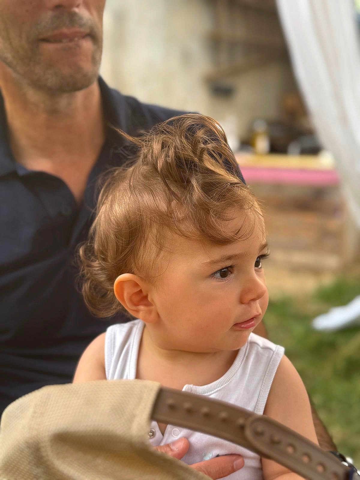 Esteban a rejoint le concours — aidez-le/la à gagner de superbes lots ! toddler, child, curly_hair, face, person, adult, hand, outdoor, grass, white_shirt, portrait, baby, skin, head, holding, background_blur, casual_clothing, nature, daylight, curious