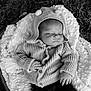 baby, infant, sleeping, knit_sweater, hood, pom_poms, blanket, basket, outdoor, grass, black_and_white, peaceful, cozy, texture, portrait, newborn, child, soft_lighting, hands, resting