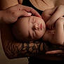 Eloann participe au concours pour gagner de l'argent avec cette photo : baby, sleeping, arms, tattoos, hand, skin, person, infant, peaceful, portrait, closeup, love, care, family, gentle, resting, human, soft_light, holding, tender