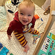 Archie is registered to the contest to win money with this photo: baby, child, smiling, sitting, play_mat, toys, hoodie, striped_pants, indoor, carpet, colorful, happy, cute, infant, playtime, person, face, young_child, floor, wooden_frame