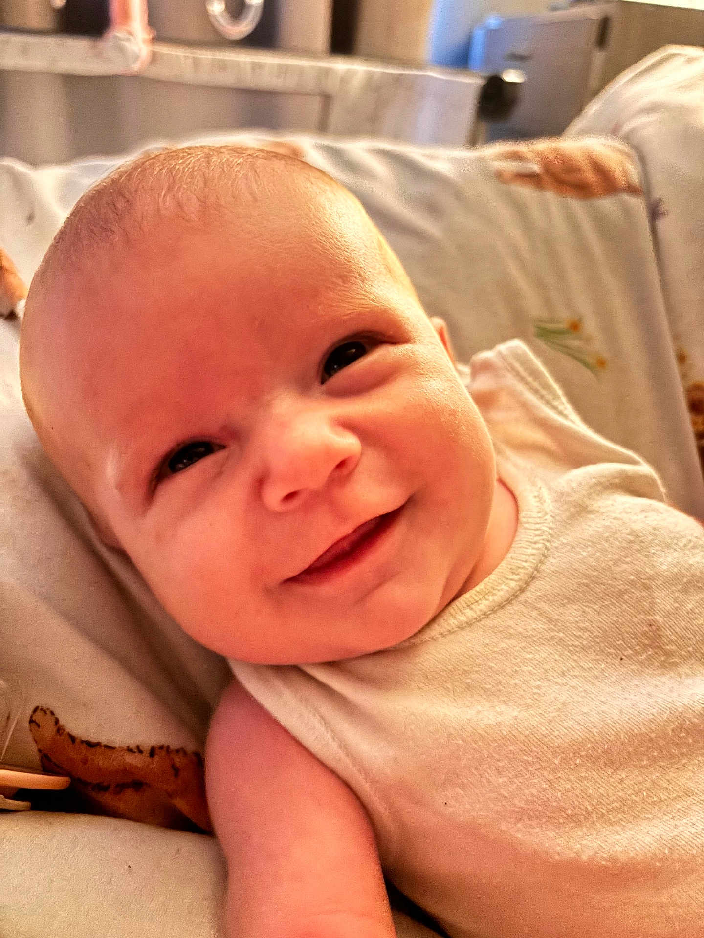 Riley-Hope joined the competition — help win amazing prizes! baby, smiling, close_up, infant, face, skin, blanket, lying_down, joyful, cute, child, young, indoors, warm_light, expression, soft, white_clothing, portrait, head, person