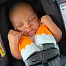 Jahlani is registered to the contest to win money with this photo: baby, black, car_seat, child, closed_eyes, comfort, cute, indoors, infant, newborn, orange, peaceful, plush_cover, portrait, resting, safety_harness, seatbelt, sleeping, small_hands, white