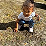 child, toddler, outdoor, dirt, grass, sunlight, shadow, curly_hair, white_shirt, blue_jeans, pink_shoes, garden_tool, playing, crouching, person, nature, daylight, ground, parked_car, young_child