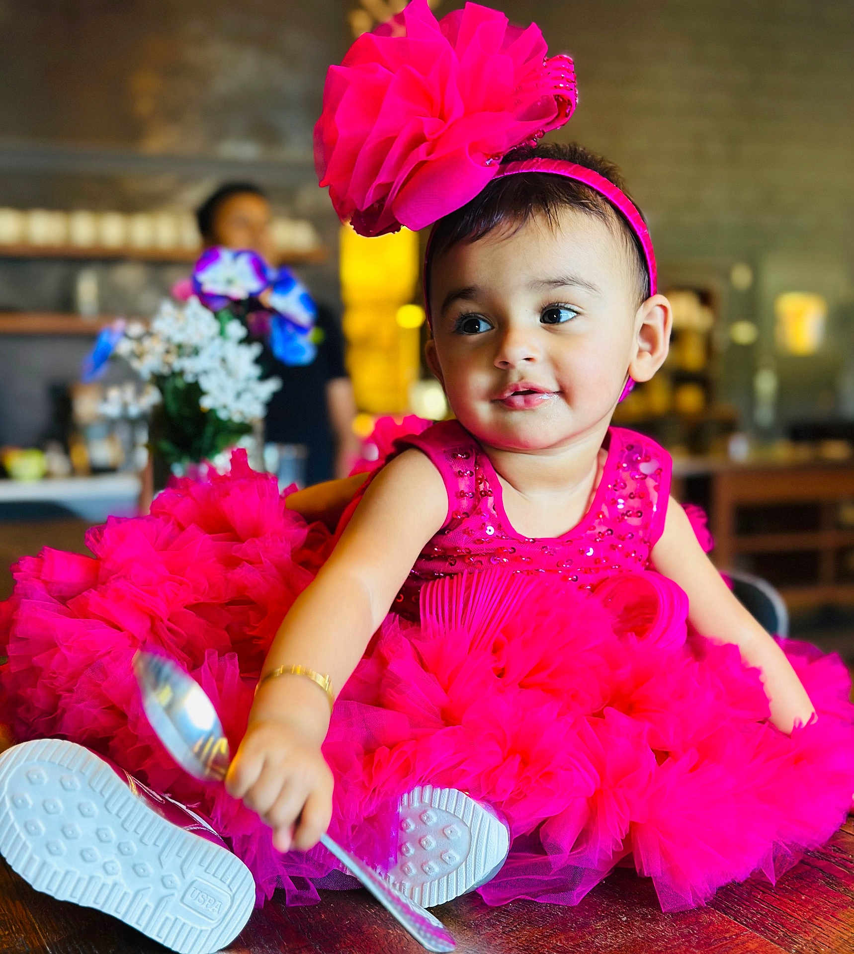 Alisha joined the competition — help win amazing prizes! toddler, child, pink_dress, headband, spoon, sitting, wooden_surface, flowers, blurred_background, indoor, person, cute, happy, playful, portrait, bright_colors, innocence, curiosity, seated, baby