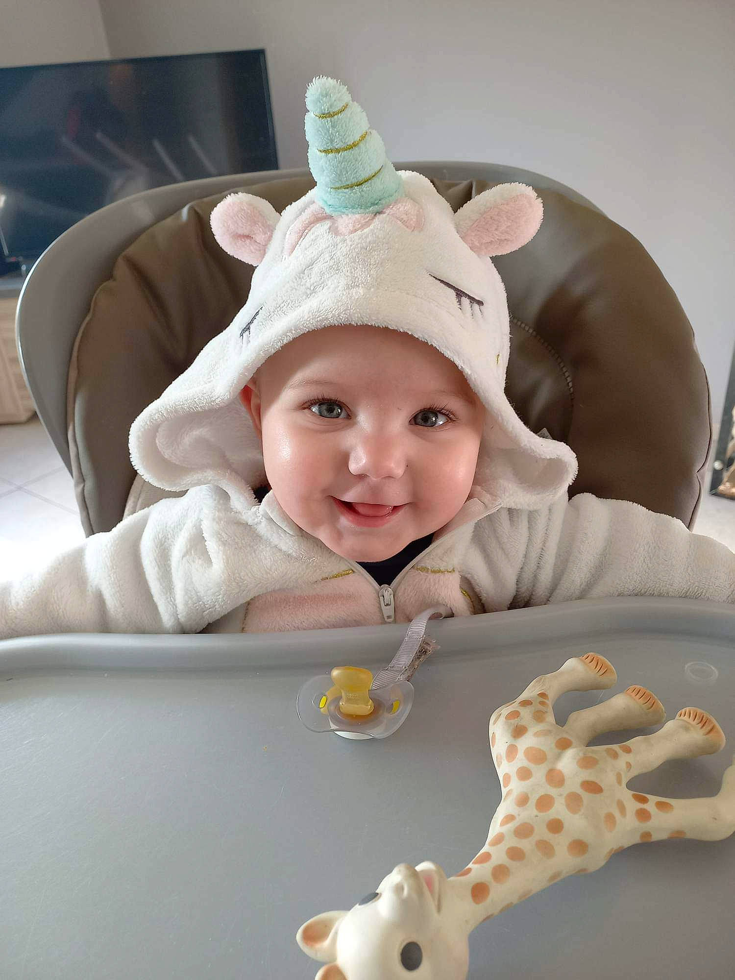 Octavia participe au concours pour gagner de l'argent avec cette photo : baby, baby_products, baby_toddler_clothing, beanie, cap, child, fashion_accessory, fun, giraffe, giraffidae, happy, headwear, joy, laugh, pattern, person, portrait_photography, room, sitting, skin
