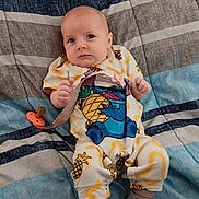 Fiona is registered to the contest to win money with this photo: baby, infant, onesie, pineapple, pacifier, blanket, striped, blue, gray, clothing, cute, child, person, sitting, indoor, soft, comfort, face, expression, sock