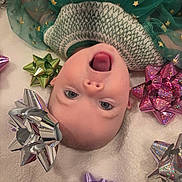 Iyla is registered to the contest to win money with this photo: baby, child, face, smile, green_dress, golden_stars, gift_bows, silver_bow, purple_bow, pink_bow, green_bow, blanket, soft_texture, holiday, festive, cute, happy, celebration, indoors, portrait