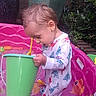 Angel is registered to the contest to win money with this photo: child, toddler, baby, outdoor, paddling_pool, water_play, bucket, toy, garden, plants, flowerpots, brick_wall, sitting, standing, concentration, long_sleeves, pajamas, wet, colorful, portrait