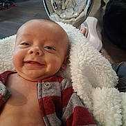 Angelemmanuel is registered to the contest to win money with this photo: baby, smile, blanket, indoor, baby_seat, clothing, face, child, person, happy, furniture, floor, plaid, red, gray, cozy, infant, cute, portrait, relaxing