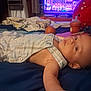 Angelemmanuel is registered to the contest to win money with this photo: baby, infant, bed, blanket, clothing, plaid, face, head, indoor, person, toy, bottle, sippy_cup, television, furniture, relaxing, lying_down, child, soft_toy, room