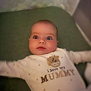 Cole joined the competition — help win amazing prizes! baby, infant, onesie, text_on_clothing, love_mummy, lying_down, green_surface, wide_eyes, cute, child, portrait, indoor, soft_lighting, small_person, adorable, face, expression, clothing, sleepwear, newborn