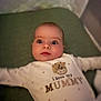 baby, infant, onesie, text_on_clothing, love_mummy, lying_down, green_surface, wide_eyes, cute, child, portrait, indoor, soft_lighting, small_person, adorable, face, expression, clothing, sleepwear, newborn