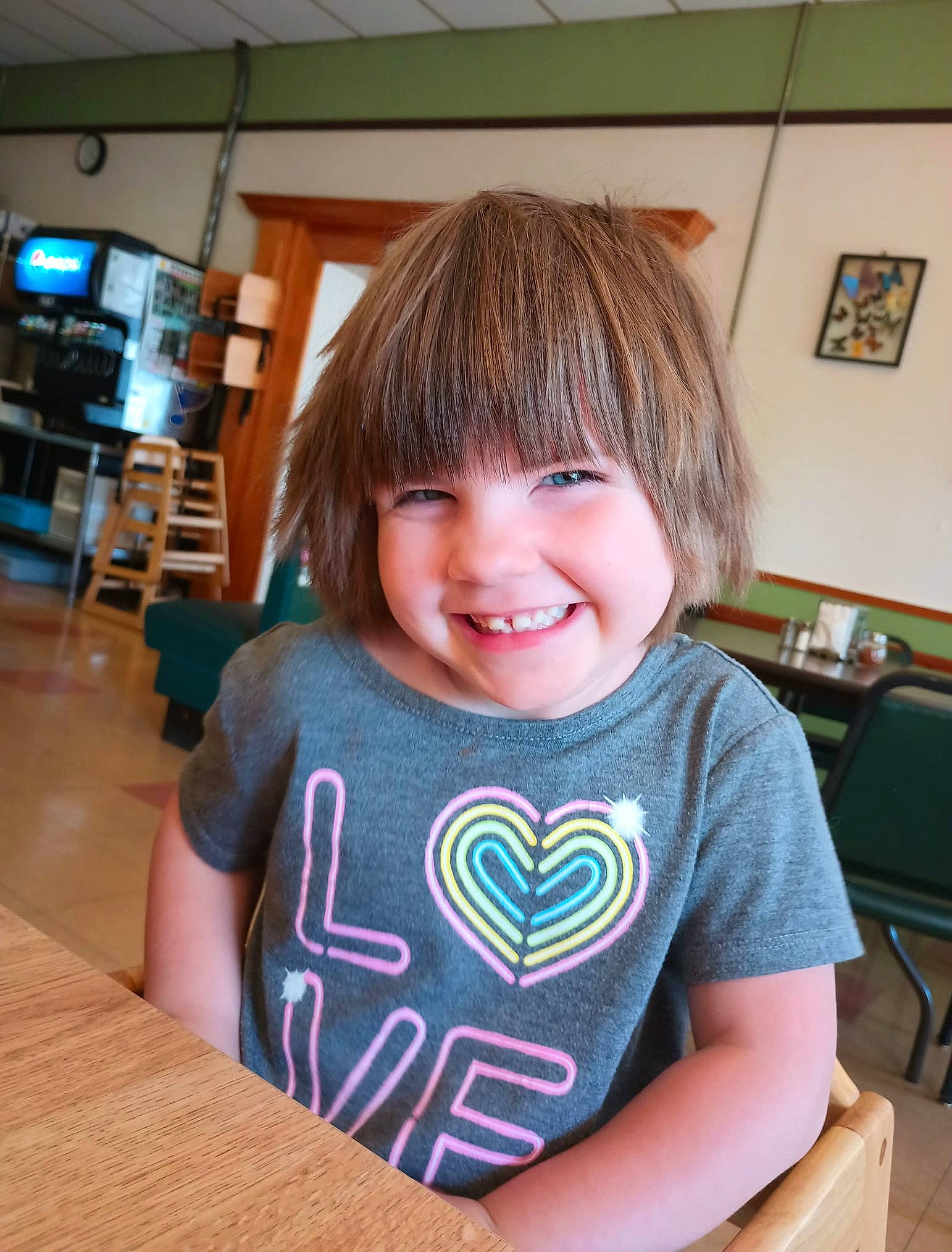 Elizabeth is registered to the contest to win money with this photo: baby_toddler_clothing, bangs, bowl_cut, chair, child, chin, facial_expression, flooring, fun, happy, hardwood, headwear, hime_cut, joy, person, room, sitting, sleeve, smile, t_shirt