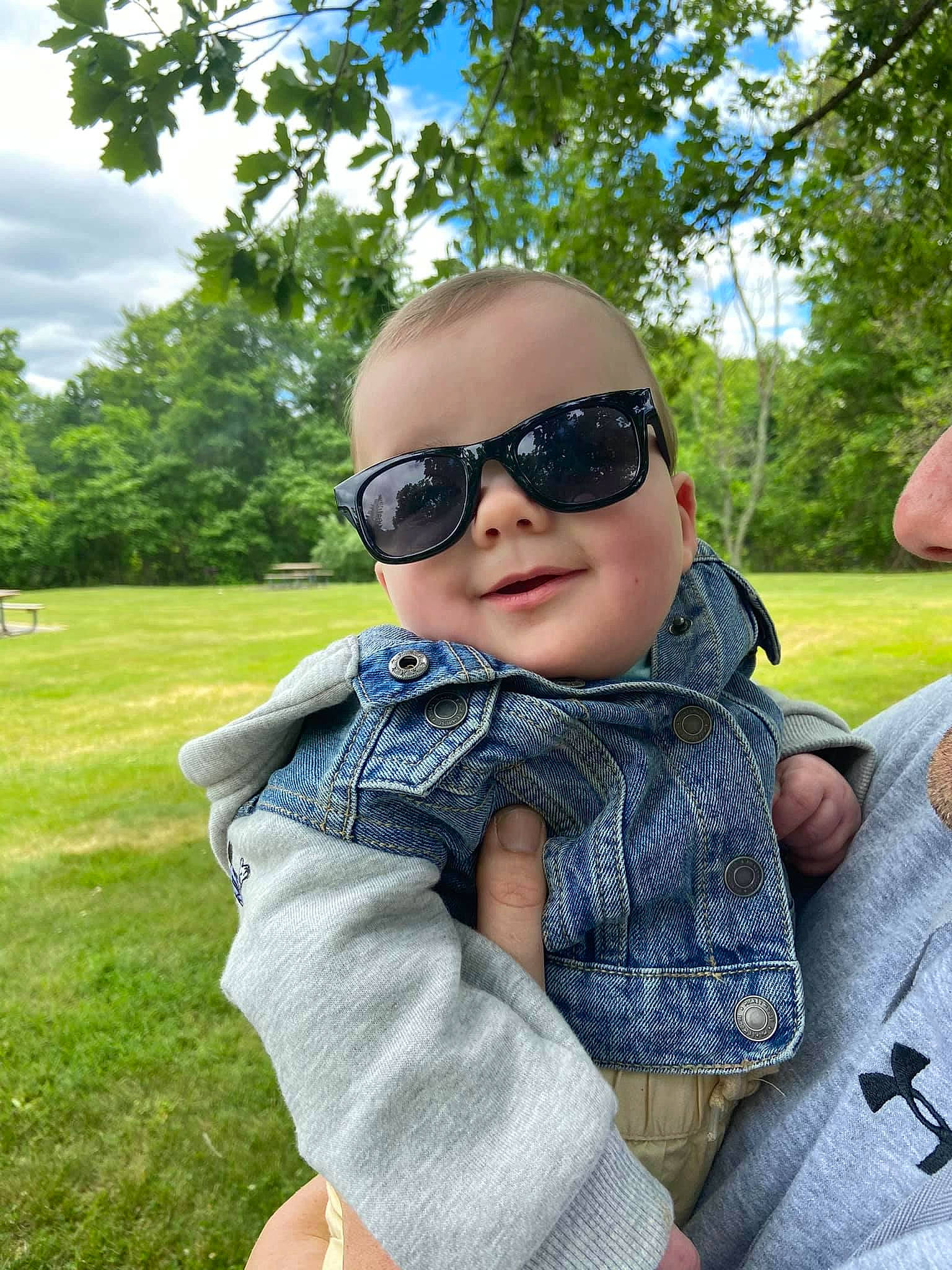 Donovan is registered to the contest to win money with this photo: baby, baby_toddler_clothing, child, eyewear, fun, glasses, goggles, grass, hand, happy, leisure, person, personal_protective_equipment, plant, recreation, sky, sunglasses, swing, toddler, tree