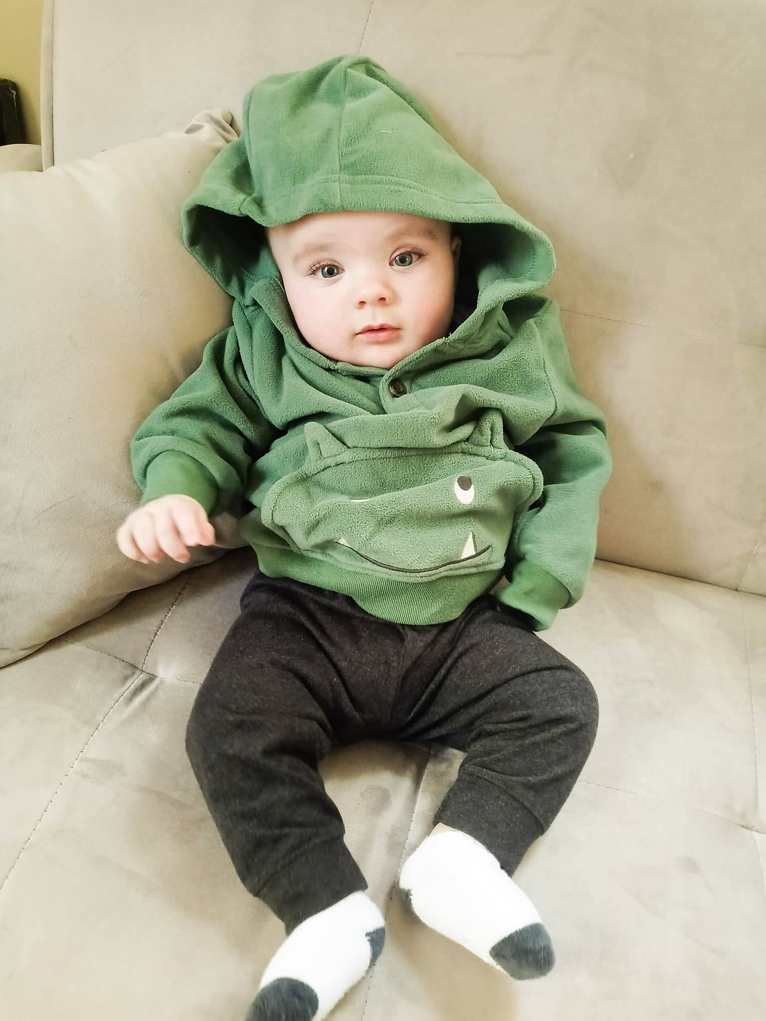 Donovan is registered to the contest to win money with this photo: arm, baby, baby_toddler_clothing, cap, child, comfort, couch, eye, fashion_accessory, flooring, foot, grass, head, headwear, human_leg, linens, person, sitting, sleeve, t_shirt