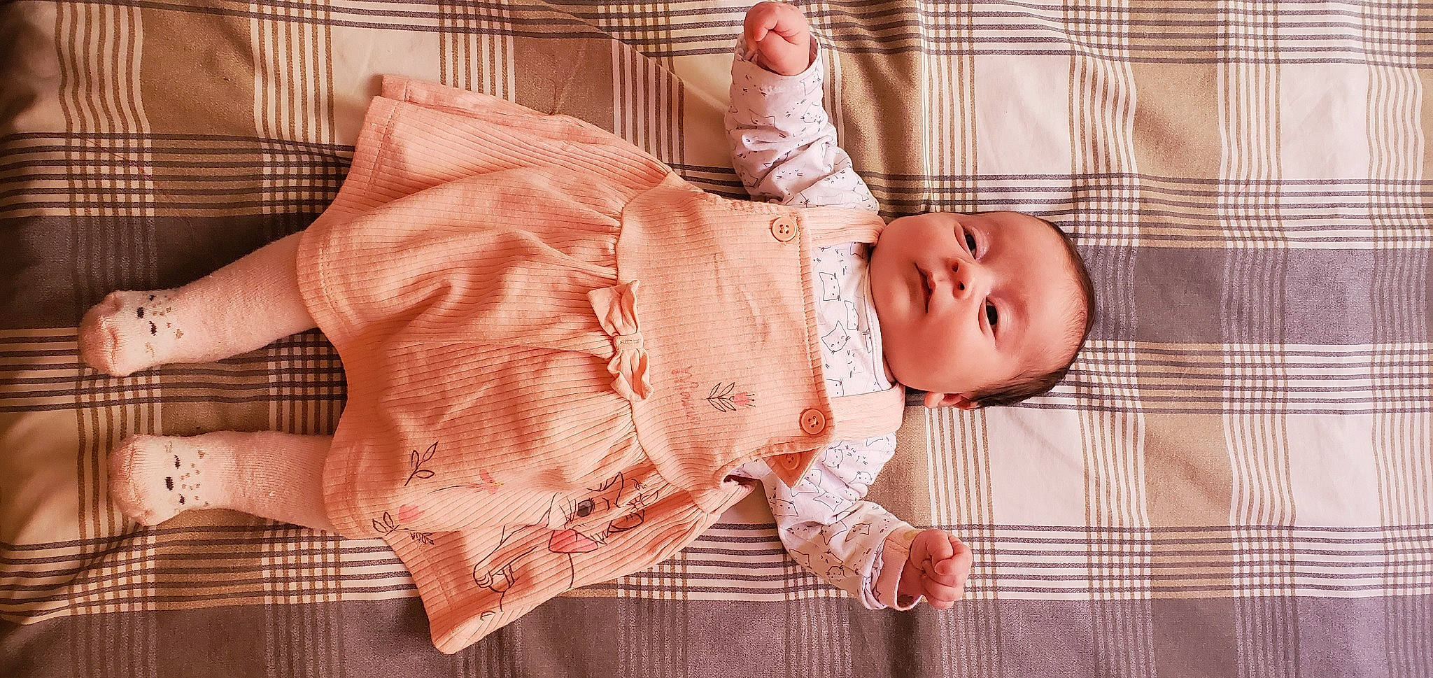Myla participe au concours pour gagner de l'argent avec cette photo : baby, baby_products, baby_safety, baby_toddler_clothing, child, comfort, dress_shirt, human_body, linens, orange, pattern, peach, person, pink, plaid, skin, sleeve, tartan, textile, toddler