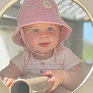 Charlotte is registered to the contest to win money with this photo: toddler, child, hat, bucket_hat, pink, striped, face, blue_eyes, hands, metal_tube, circle_frame, curious, outdoor, soft_light, portrait, baby, clothing, person, skin, candid