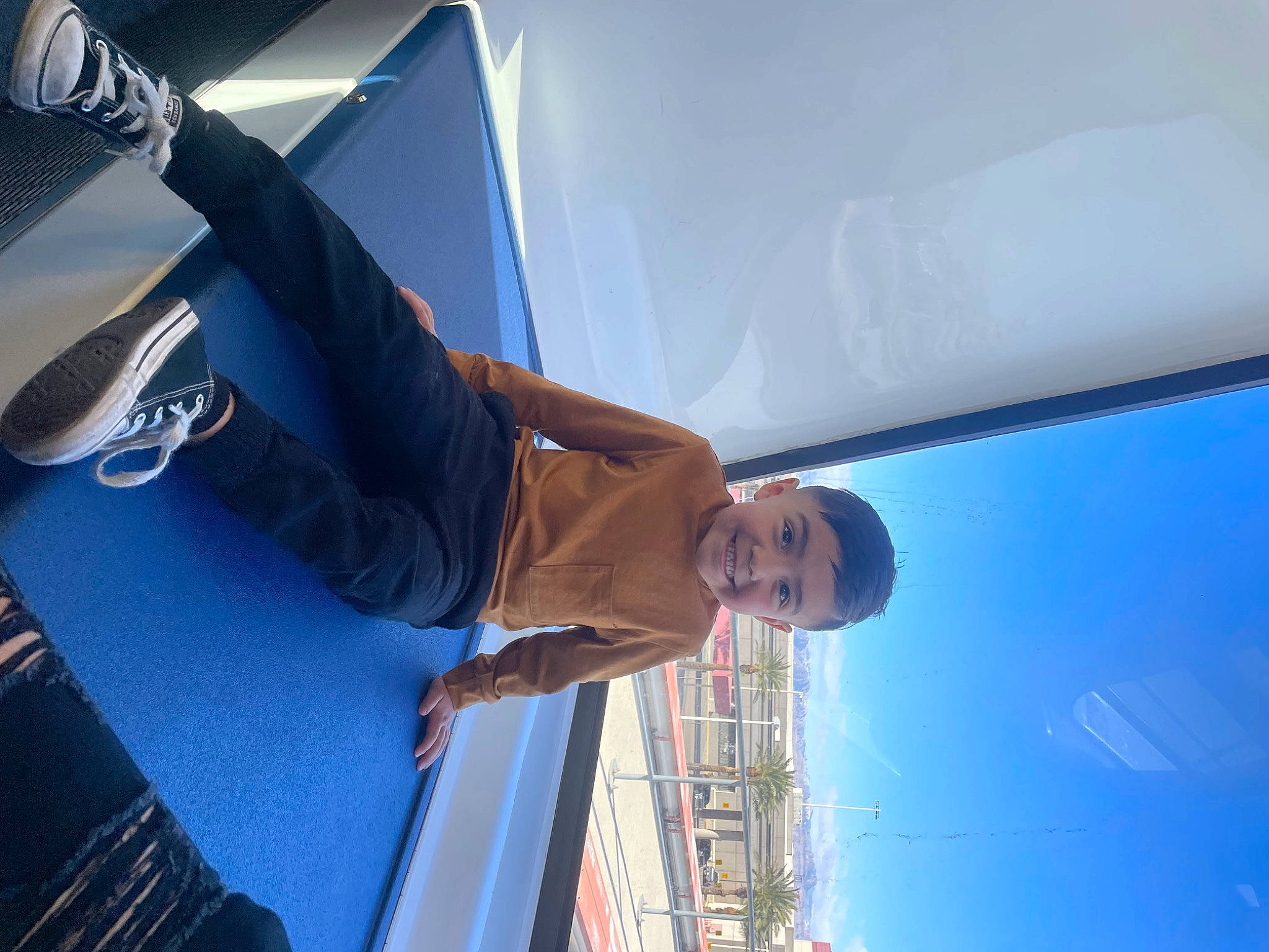 Miguel is registered to the contest to win money with this photo: automotive_design, automotive_exterior, azure, building, elbow, electric_blue, fun, gesture, human_leg, joy, leisure, luxury_vehicle, person, sky, smile, sportswear, transport, travel, window