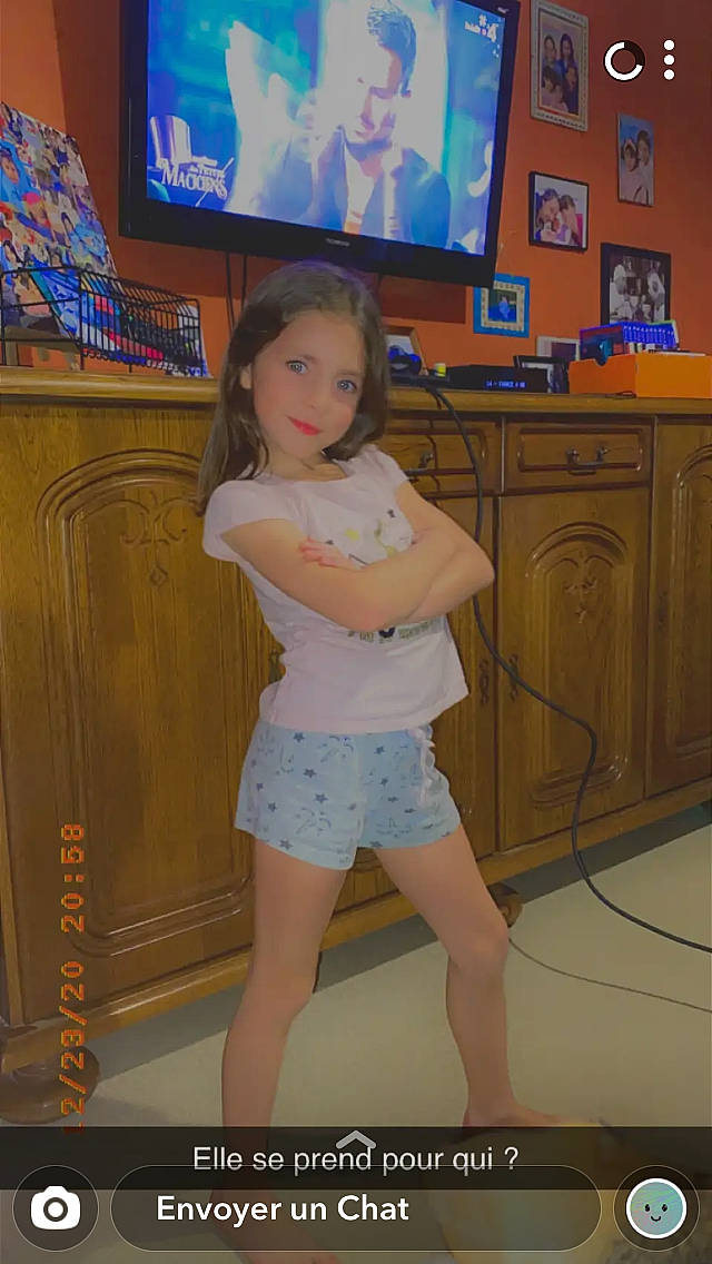 Julia participe au concours pour gagner de l'argent avec cette photo : blue, cable_television, floor, flooring, home_appliance, jean_short, joint, knee, leg, long_hair, neck, person, picture_frame, shorts, sportswear, standing, television, television_set, thigh, trunk