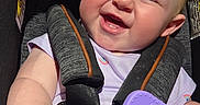 Coriann is registered to the contest to win money with this photo: baby, infant, child, smiling, happy, laughing, car_seat, harness, remote_control, purple, close_up, portrait, indoor, vehicle, seated, baby_clothing, short_sleeves, chubby_cheeks, joyful, photography
