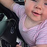 Coriann is registered to the contest to win money with this photo: baby, child, infant, portrait, smiling, happy, car, steering_wheel, driver, pink_clothing, striped_shirt, short_sleeves, sitting, indoor, vehicle, dashboard, window, greenery, close_up, photograph