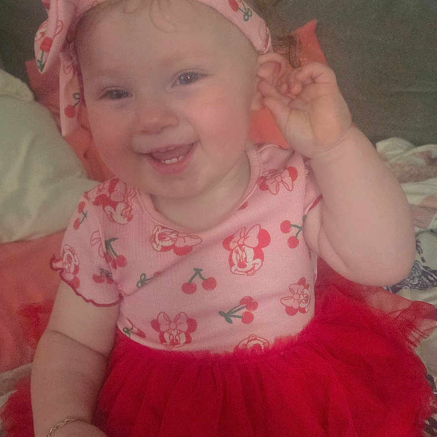 Coriann joined the competition — help win amazing prizes! baby, child, smiling, portrait, indoors, sitting, pink, red, tutu, dress, headband, minnie_mouse, cartoon, bed, blanket, couch, happy, baby_fashion, facial_expression, photography