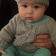 Sara participe au concours pour gagner de l'argent avec cette photo : baby, child, knitted_hat, knitted_sweater, knitted_booties, pink_blanket, teddy_bear_pattern, indoor, person, hands, cute, portrait, seated, warm_clothing, infant, soft_lighting, close_up, face, eyes, expression