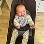 baby, smiling, babybjorn, chair, bib, onesie, dinosaur_pattern, disney_characters, happy, infant, clothing, footed_pajamas, wooden_floor, indoor, baby_boy, seated, cute, child, person, portrait