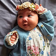 Talia joined the competition — help win amazing prizes! baby, infant, headband, flower_crown, blue_cardigan, floral_dress, hand, face, eyes, smile, cute, lying_down, blanket, soft_texture, portrait, indoors, child, newborn, skin, adorable
