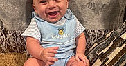 Axel joined the competition — help win amazing prizes! baby, child, infant, smiling, happy, portrait, sitting, couch, blanket, cushion, blue_outfit, striped_shirt, bodysuit, indoor, home, furniture, cozy, grinning, barefoot, photography