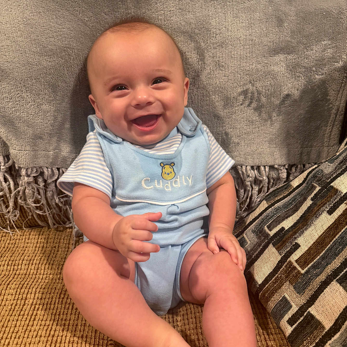 Axel joined the competition — help win amazing prizes! baby, child, infant, smiling, happy, portrait, sitting, couch, blanket, cushion, blue_outfit, striped_shirt, bodysuit, indoor, home, furniture, cozy, grinning, barefoot, photography