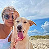 beach, casual, clouds, collar, dog, fence, grass, happy, leash, nature, outdoor, pet, portrait, sand, sky, smile, sunglasses, sunny, tattoo, woman