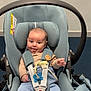 baby, car_seat, child, infant, blue, clothing, cute, face, happy, indoors, infant_seat, person, playful, sitting, smiling, straps, tongue, young_child, seatbelt, head_support